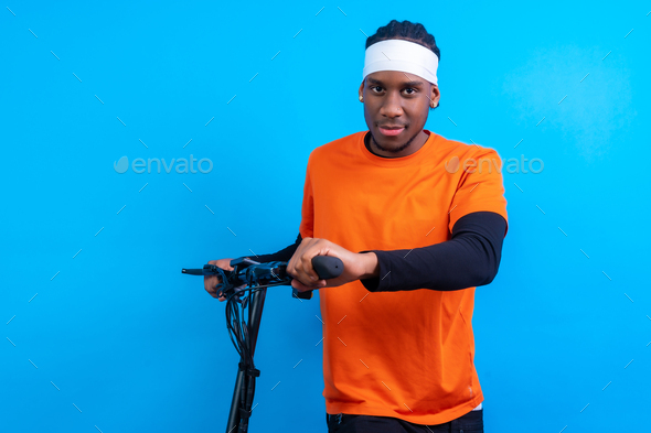 Black ethnic man in orange clothes on a blue background, with an electric skateboard