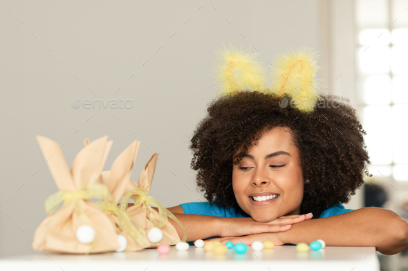 Easter Celebration. Happy Black Lady Wearing Bunny Ears Posing With Gift Bags