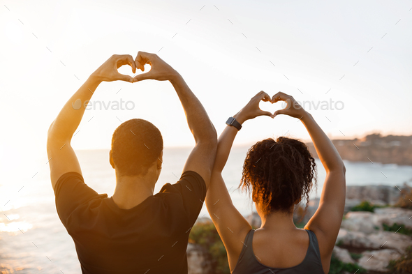 Happy young african american couple enjoy workout break, make heart with hands sign in morning on