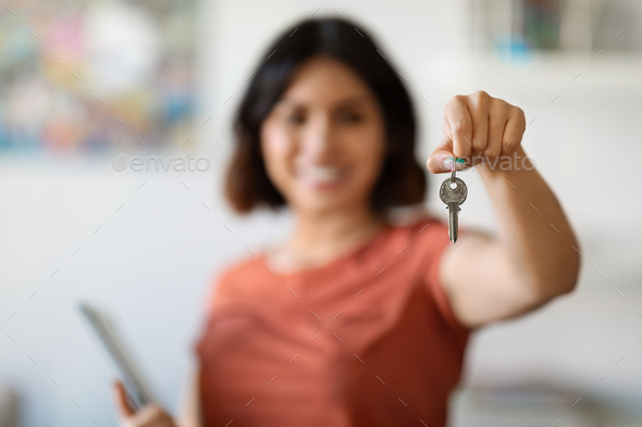 Smiling Young Female Real Estate Agent Holding Clipboard And Showing Home Keys