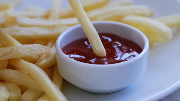 Child eats fries, dips potatoes in red ketchup sauce. Fast food is not good for the body.