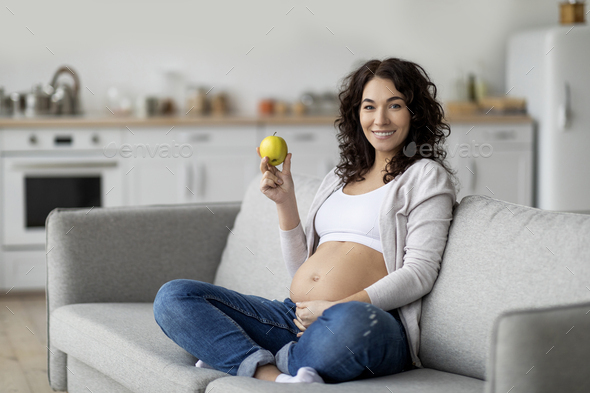 Pregnancy Diet. Smiling pregnant woman holding green apple and touching ...