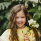 Cute little girl in a yellow dress, holding spring flowers in her hands, standing against  - PhotoDune Item for Sale