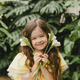 Cute little girl in a yellow dress, holding spring flowers in her hands, standing against - PhotoDune Item for Sale