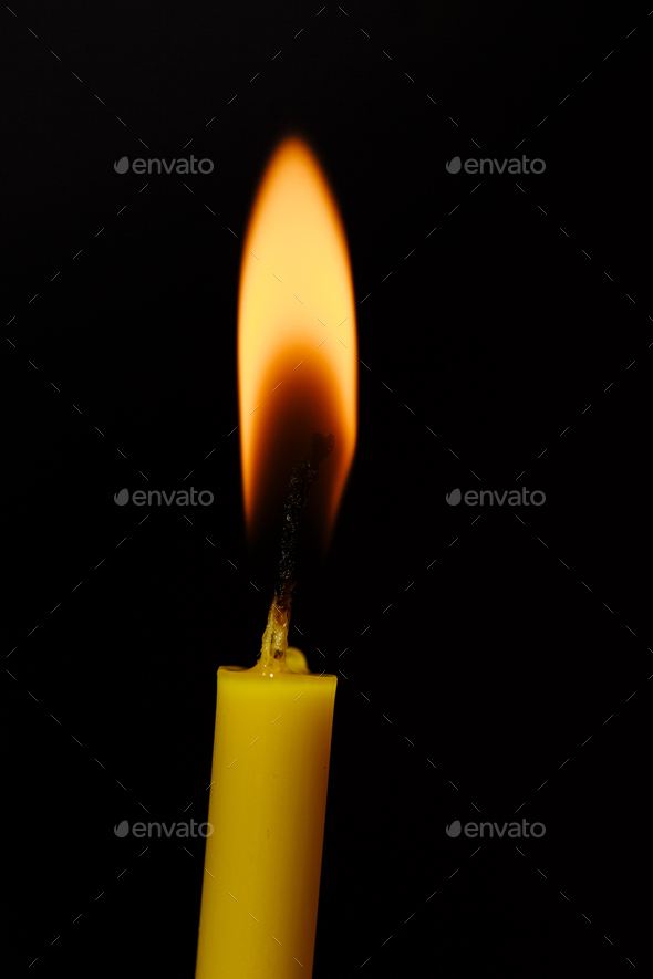Burning candle on black background. Candle light. The flame of candle light. Stock Photo by