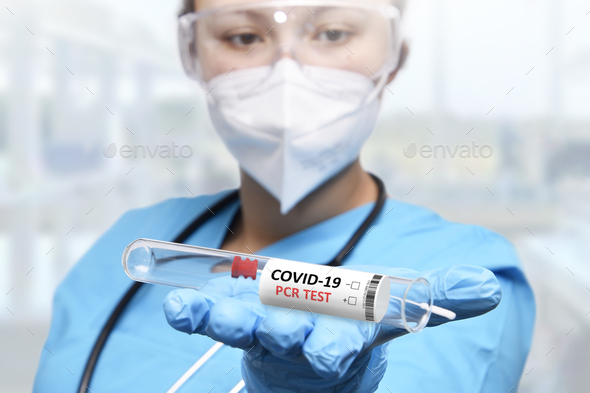 NHS technician holding COVID-19 swab collection kit wearing white PPE protective suit and mask