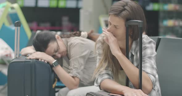 Exhausted Young Woman Sleeping on Travel Bag As Mid-adult Lady Sleep at the Background on Suitcase alt