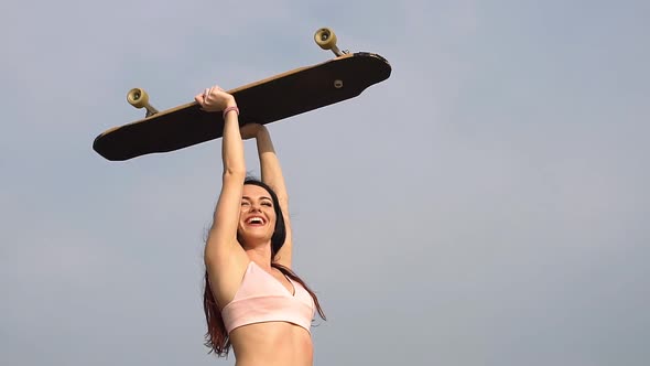 Portrait of a Hipster Young Girl Smiling with a Longboard. Slow Motion