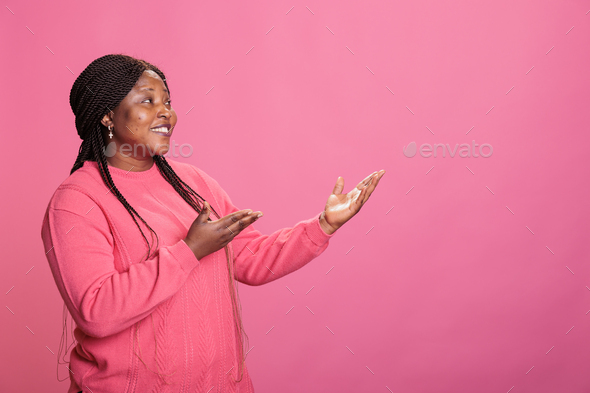 Portrait of smiling woman advertising promotional product in studio