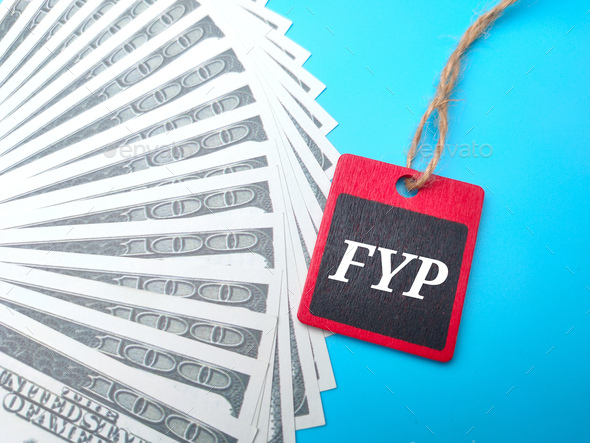 Banknotes and wooden board with the word FYP. - Stock Photo - Images
