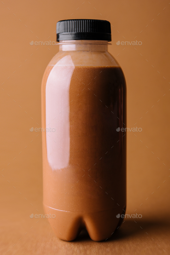Brown smoothies in a bottle on a brown background