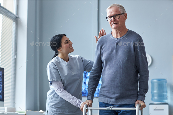 Nurse helping senior man using mobility walker in retirement home