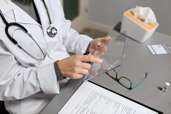 Unrecognizable female doctor touching with finger transparent tablet - Stock Photo - Images