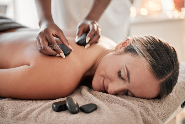 Woman, hot stone massage and therapist, hands and zen with holistic therapy and spa treatment for b