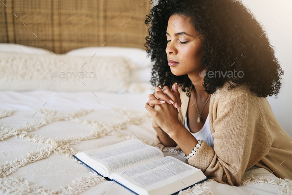 Bible, prayer and black woman praying on bed in bedroom home for hope, help  or spiritual faith. God Stock Photo by YuriArcursPeopleimages