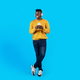 Smiling Black Guy In Wireless Headphones Holding Smartphone And Looking Away - PhotoDune Item for Sale
