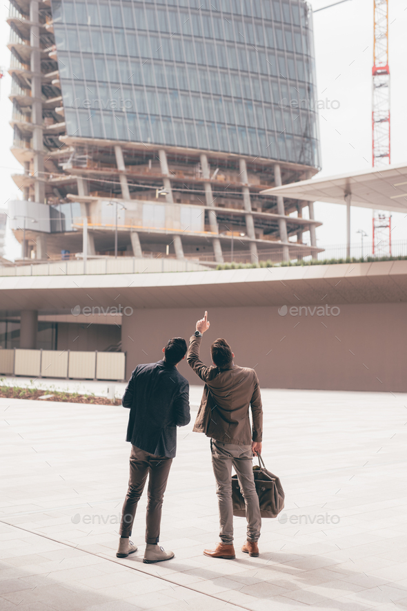 Two young contemporary businessmen back view outdoors city looking cityscape - Stock Photo - Images