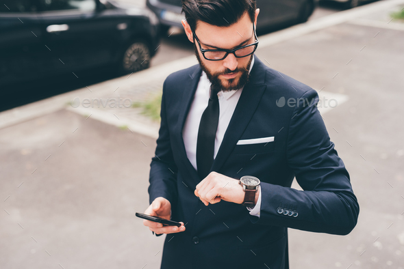 Young professional elegant bearded businessman checking time - Stock Photo - Images
