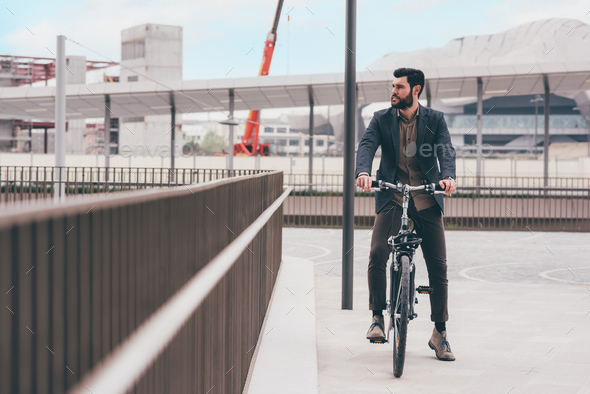 Contemporary bearded young stylish businessman going to work by bike - Stock Photo - Images