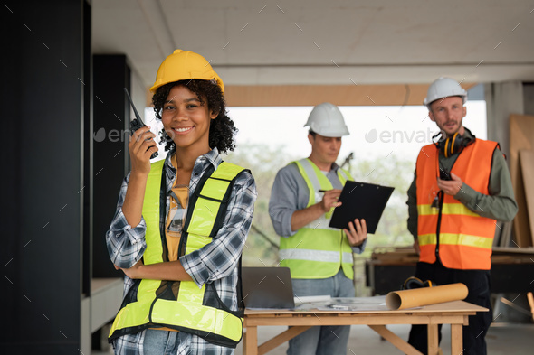 Portrait of female engineer holding walkie talkie and male engineer with working together - Stock Photo - Images