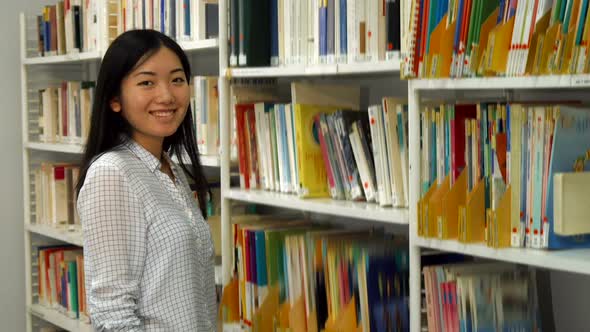 Girl Puts Academic Journals on the Rack at the Library alt