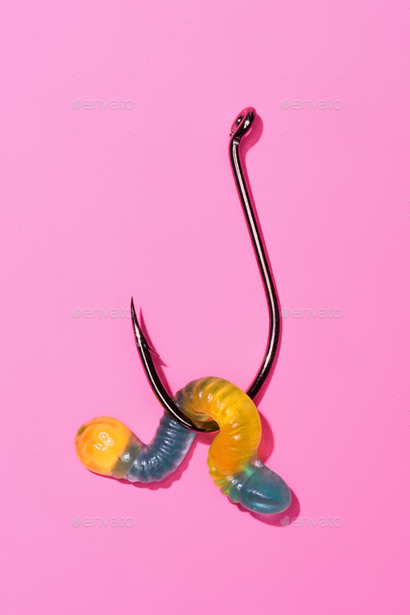 colorful gummy worm on fishing hook on pink