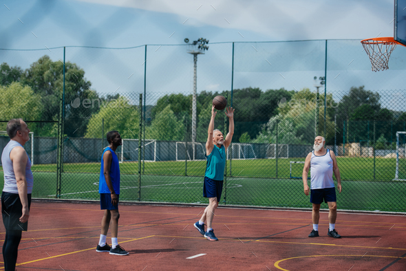 interracial elderly sportsmen playing basketball together on playground