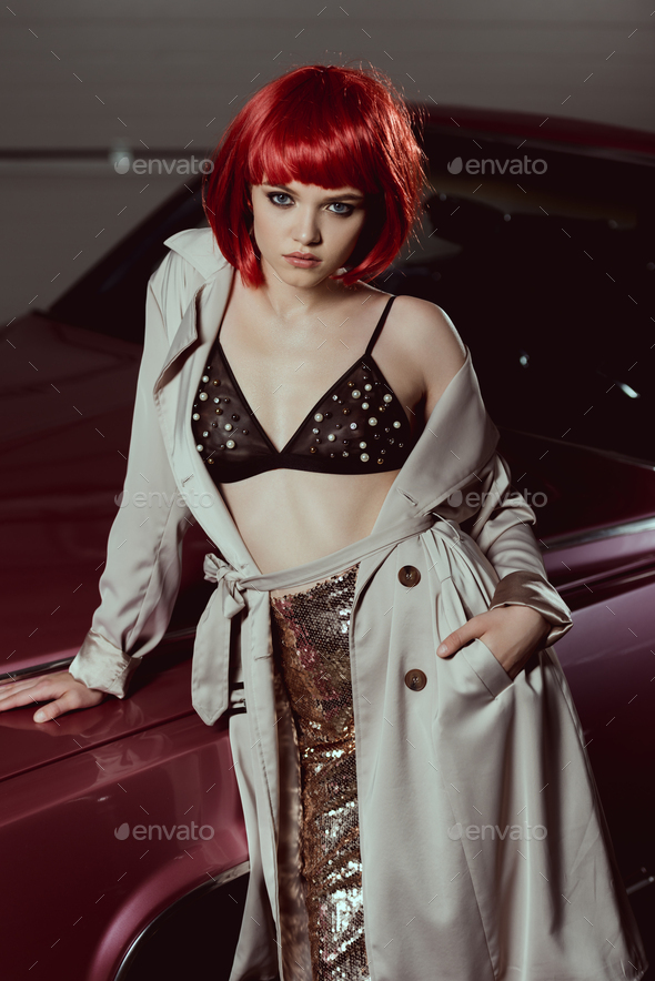 high angle view of stylish girl in trench coat and bra leaning at car and  looking at camera Stock Photo by LightFieldStudios