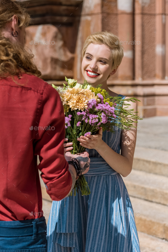 cropped image of boyfriend presenting bouquet of flowers to girlfriend