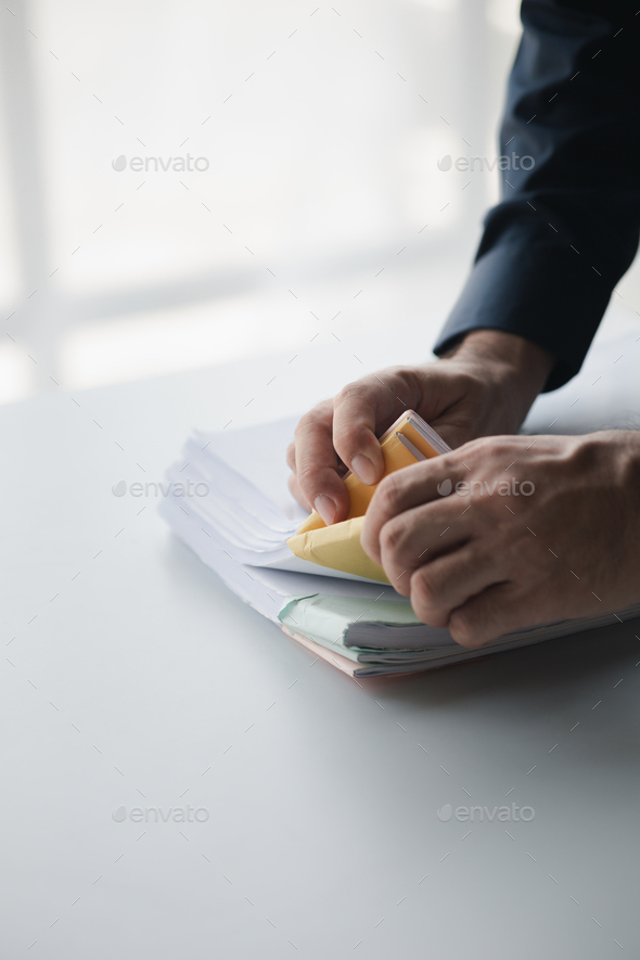 Businessman sorting stacks of department meeting papers, document management in corporate office. Of