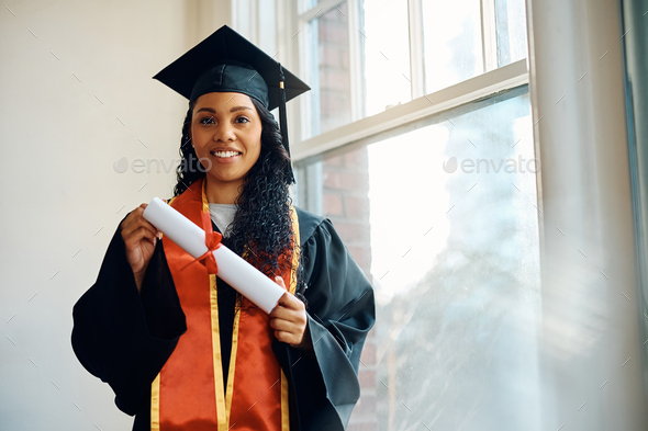 Happy black graduate student with her university diploma looking at camera.