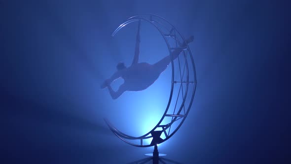 Aerial Acrobatics the Girl Weighs in a Twine on a Design in the Form of a Month and She Turns. Blue alt