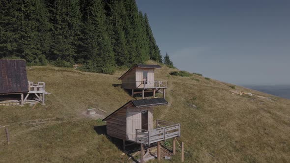 Hiker female standing outdoors near wooden house in the mountains alt