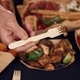 Man is holding fork with mushroom. Close up view of table with food on it. Meat, vegetables - PhotoDune Item for Sale