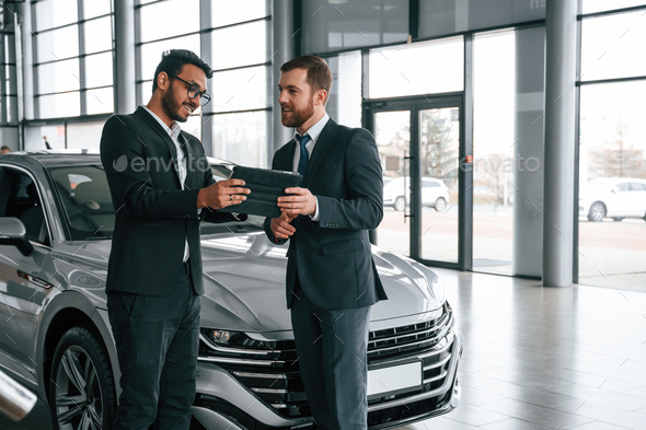 Standing and talking near automobile. Man is consulting the customer in ...