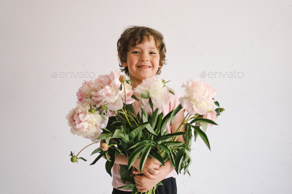 Cheerful happy child with Peonys bouquet. Smiling little boy on white background. - Stock Photo - Images