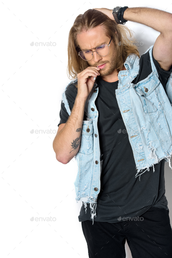 handsome young man in denim vest smoking roll up cigarette on white