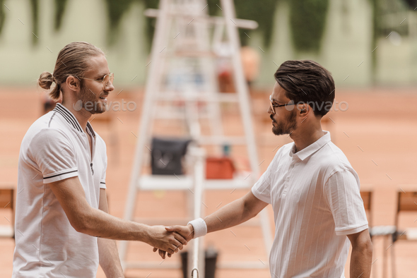 side view of retro styled tennis players shaking hands before game at tennis court