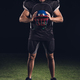 american football player standing on green grass and holding helmet in hands on black - PhotoDune Item for Sale