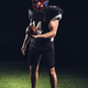 handsome american football player with ball looking at camera on black - PhotoDune Item for Sale