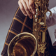 close-up partial view of stylish professional musician holding saxophone on grey - PhotoDune Item for Sale