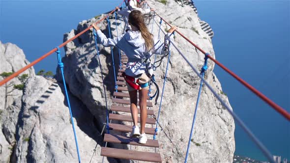 Girls Crossing the Chasm on the Rope Bridge. Black Sea Background, Crimea