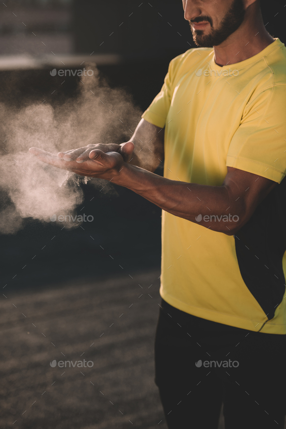 cropped image of sportive man clapping hands with talc powder on roof
