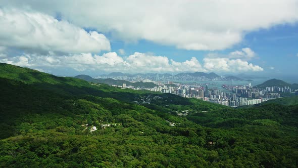 A dynamic high altitude aerial footage revealing the cityscape of Hong Kong surrounded by trees, the alt