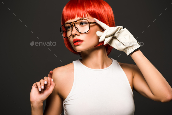 beautiful young woman with red bob cut in golf glove and stylish eyeglasses isolated on grey