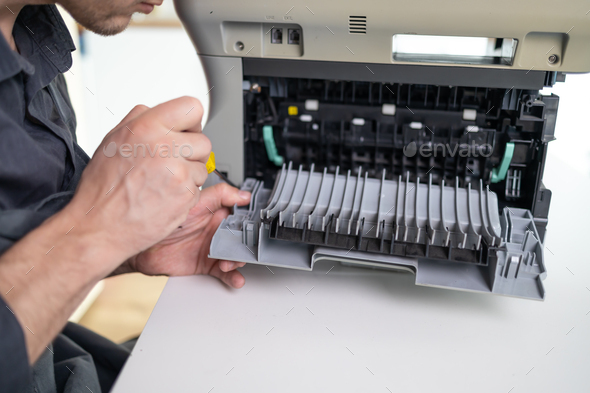 Specialist repairs the printer cartridge, fuser unit close-up. printer repair technician.