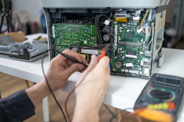 printer repair technician. A male handyman inspects a printer before starting repairs in a client\'s