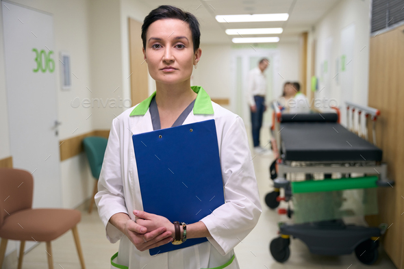 Nurse stands with a blue folder in the corridor