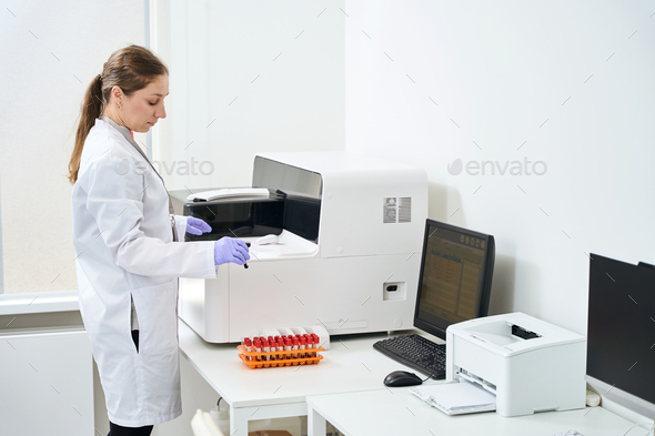 Woman doctor stands near a hematological analyzer in testing unit
