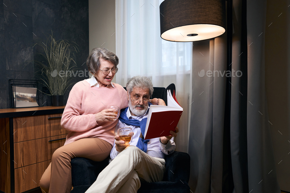 Cute grandparents settled down in an armchair with a book